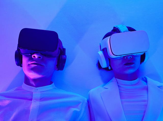 pexels-michelangelo-buonarroti-8728560 Personen mit VR-Headsets, beleuchtet in blauem und violettem Licht, erleben virtuelle Realität.